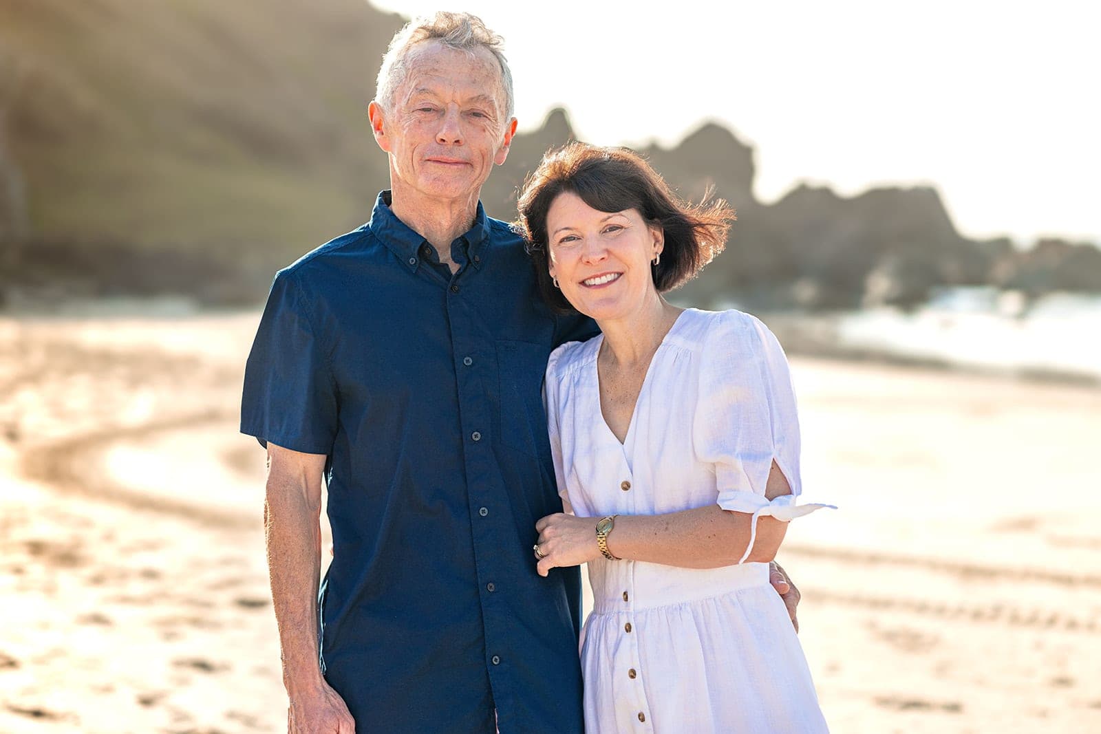 Husband and wife cheek to cheek, laughing on the beach