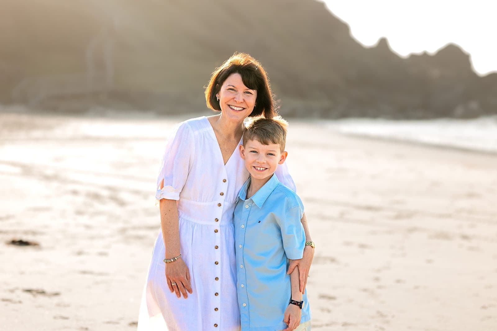 Mum hugging her son on the beach, both smiling