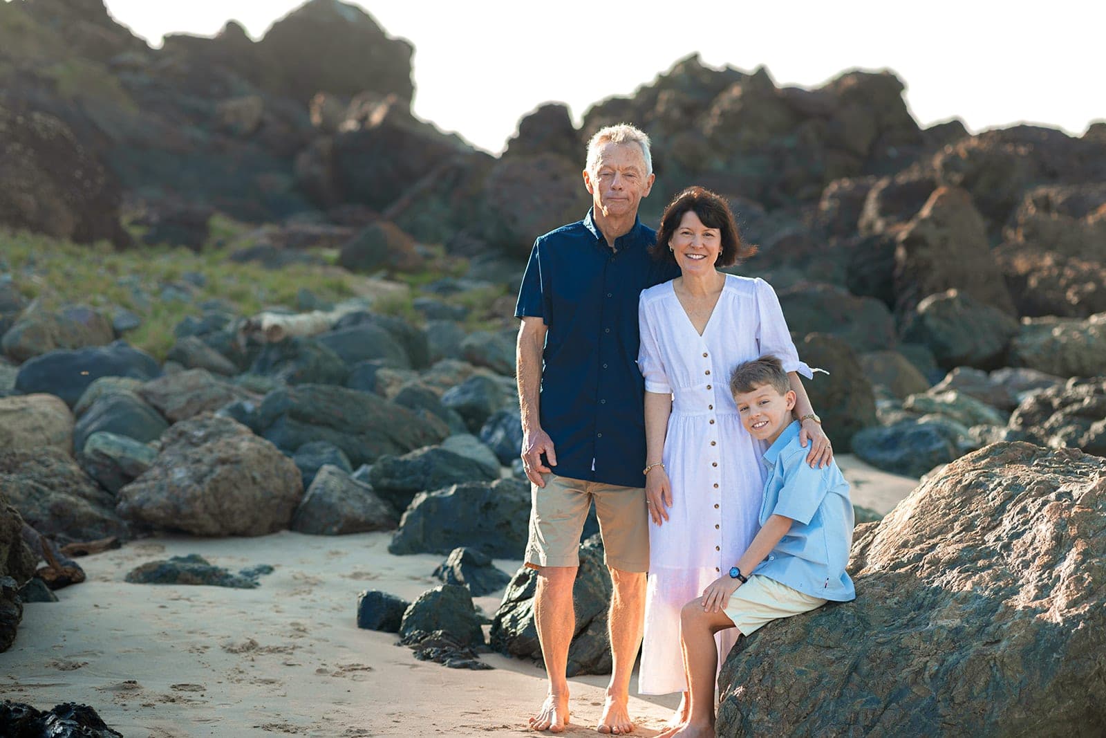 Family sitting together on a large rock at the beach