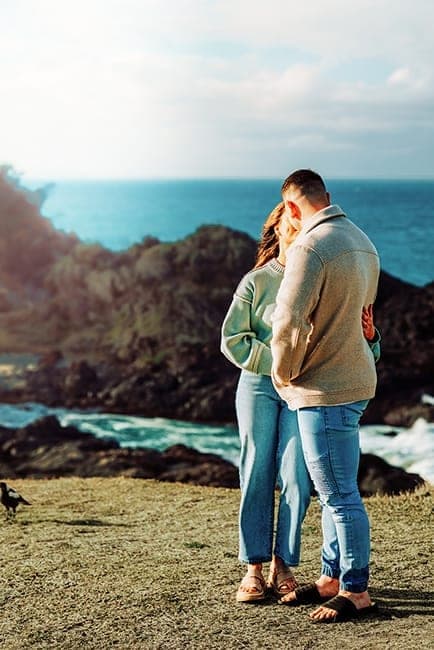 Couple holding each other on a clifftop above the sea