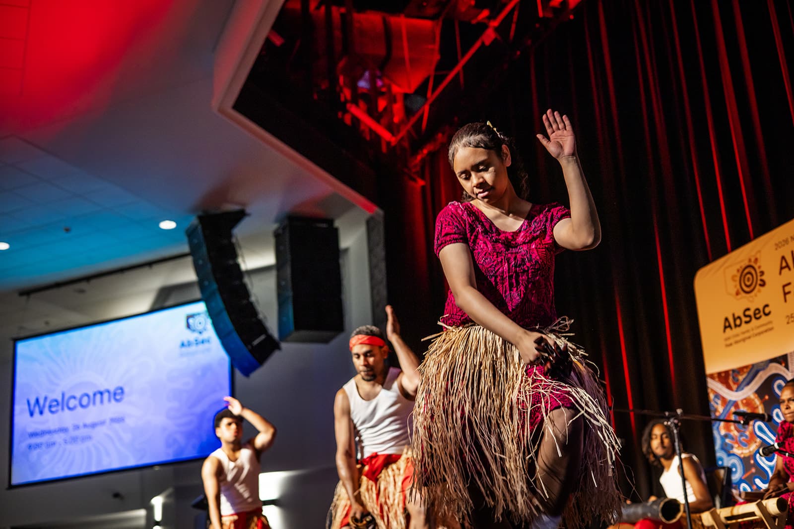 A dancer performing on stage under red lights at the AbSec 2026 conference