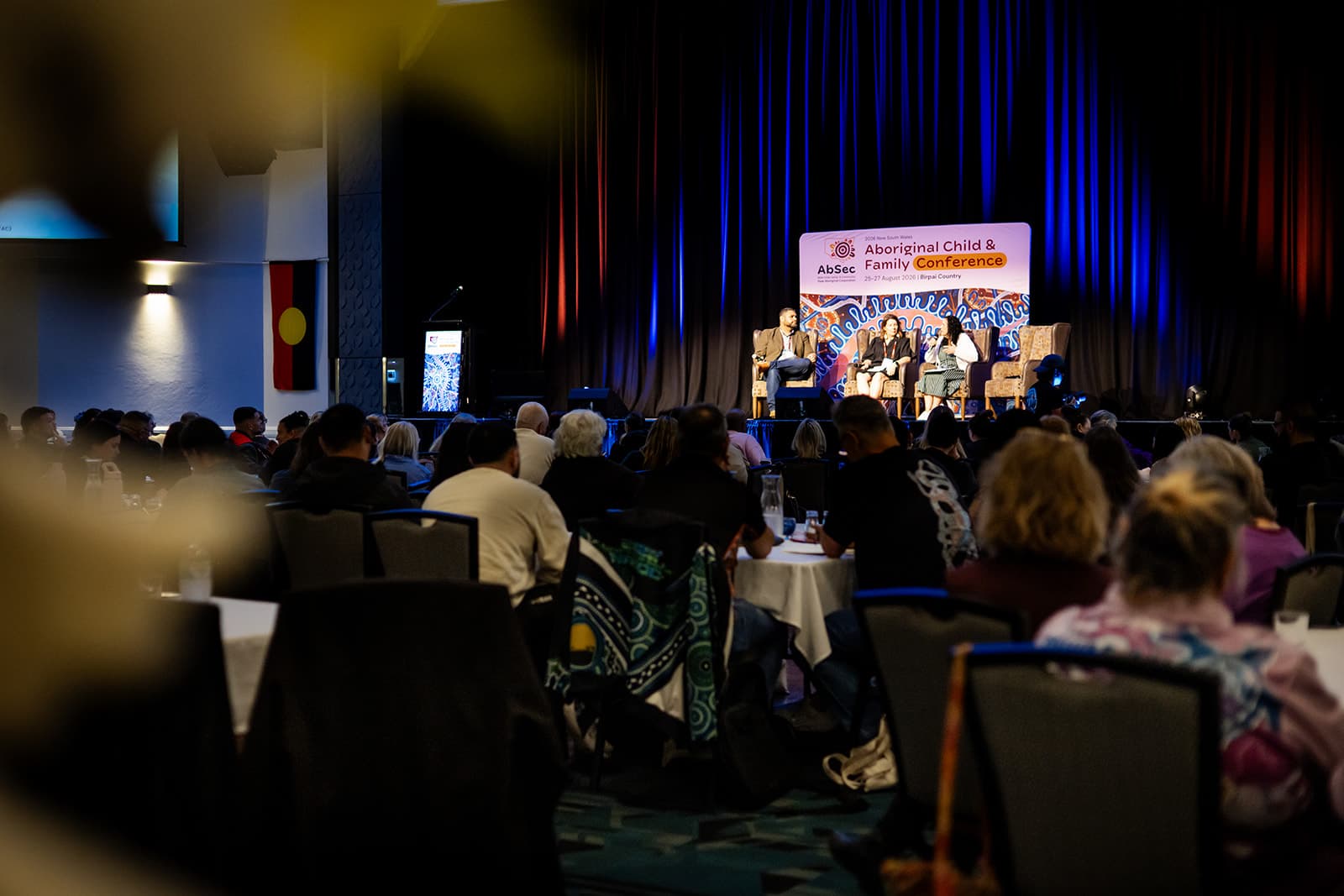 A full conference room of AbSec delegates watching a panel on stage