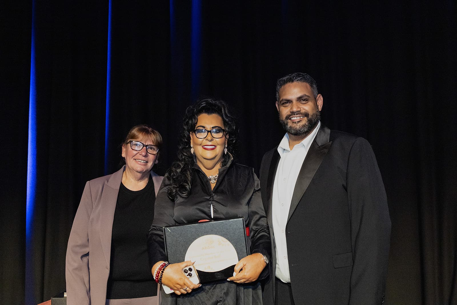 An award recipient holding her plaque alongside the presenters