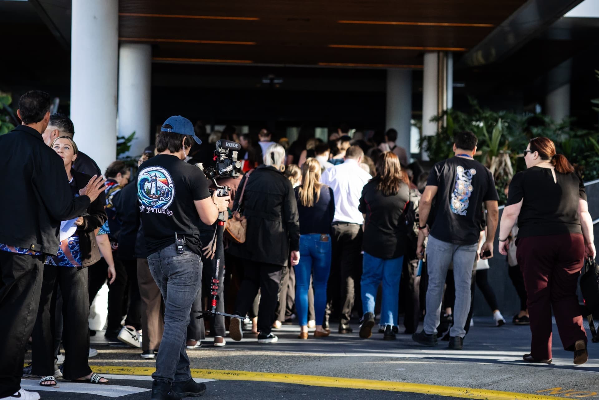 Camera operator filming a crowd at an event entrance