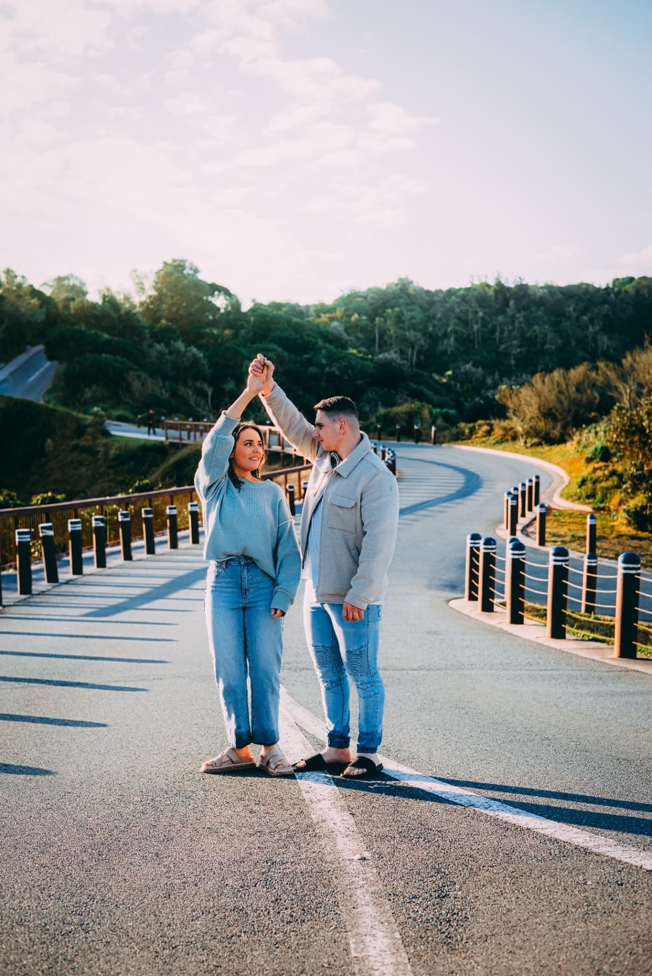Couple dancing on a coastal road beside a timber boardwalk
