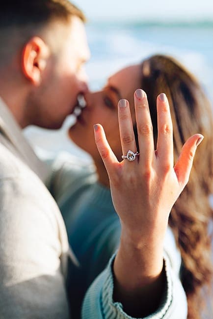 Close kiss with the engagement ring in sharp focus