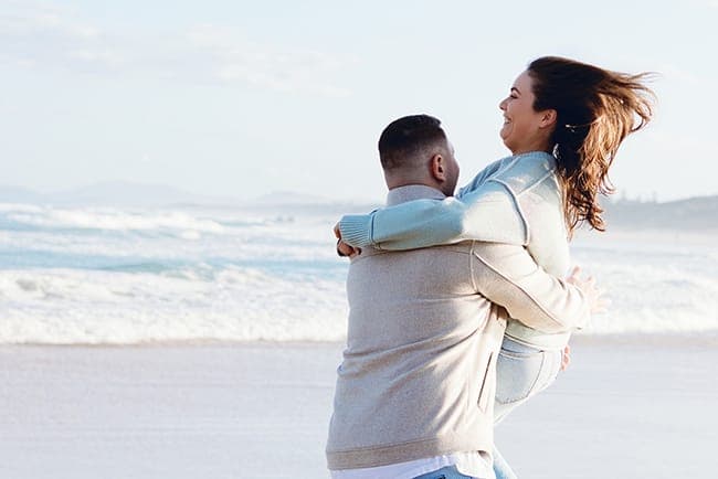 Joseph lifting and spinning Tia at the water's edge