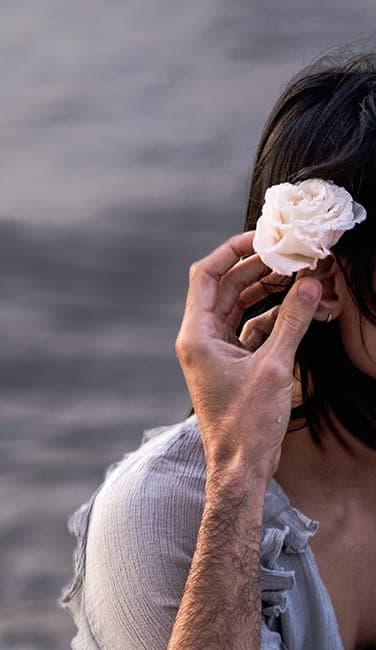 Detail of a hand tucking a frangipani behind her ear
