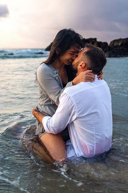 Couple laughing nose to nose while sitting in the shallows