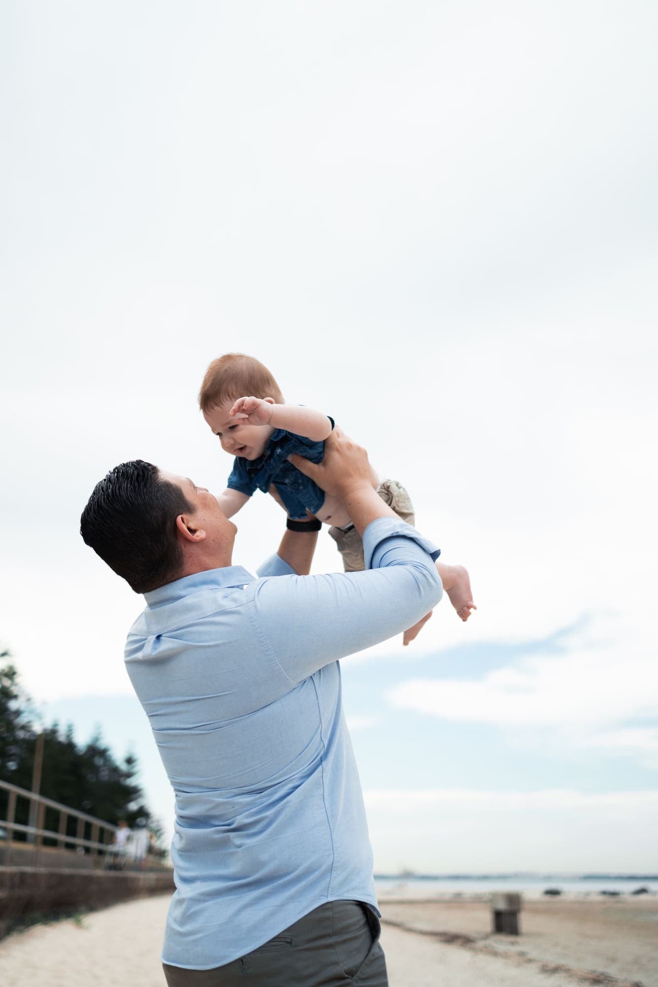 Father lifting his baby into the sky at the beach