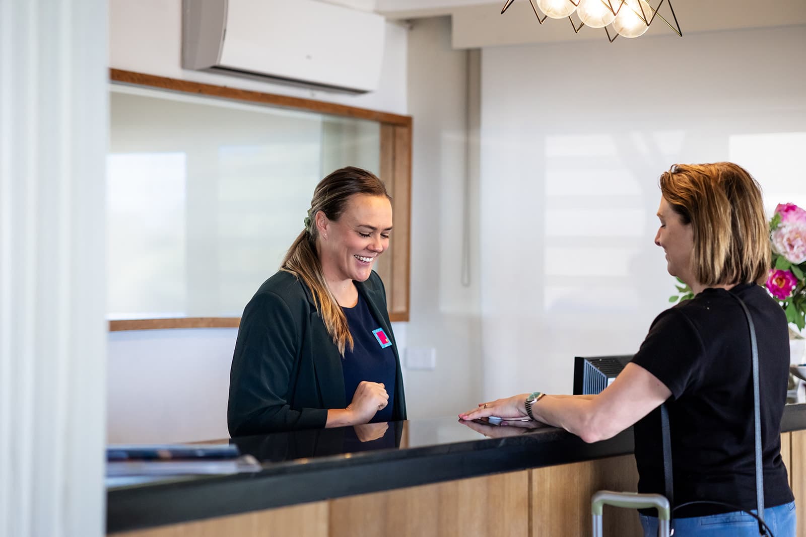 Receptionist smiling while checking in a guest at the front desk