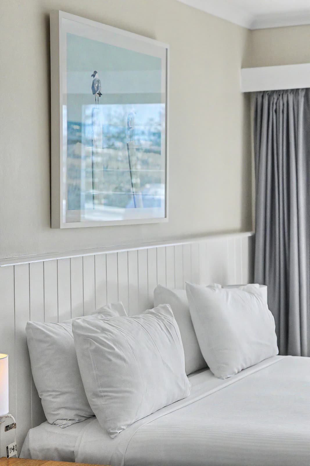 Plumped white pillows below a framed seagull print