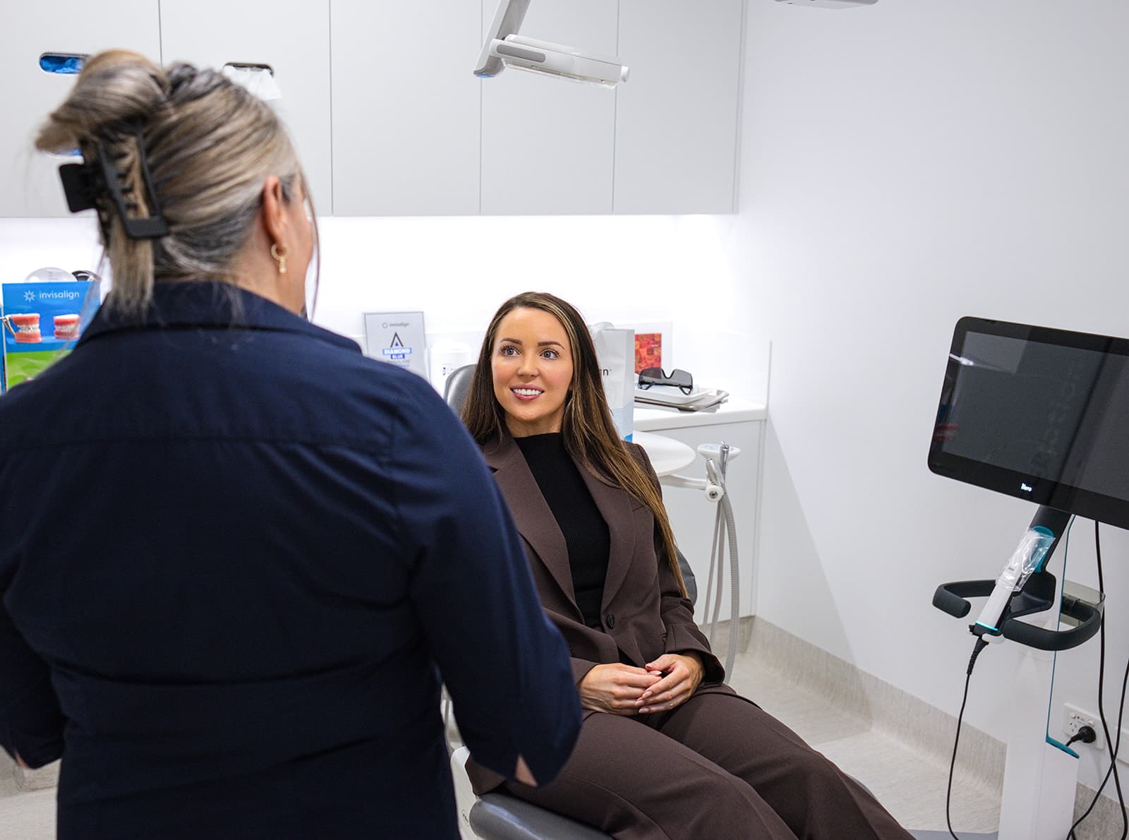 Smiling patient in the treatment chair chatting with a team member before her scan