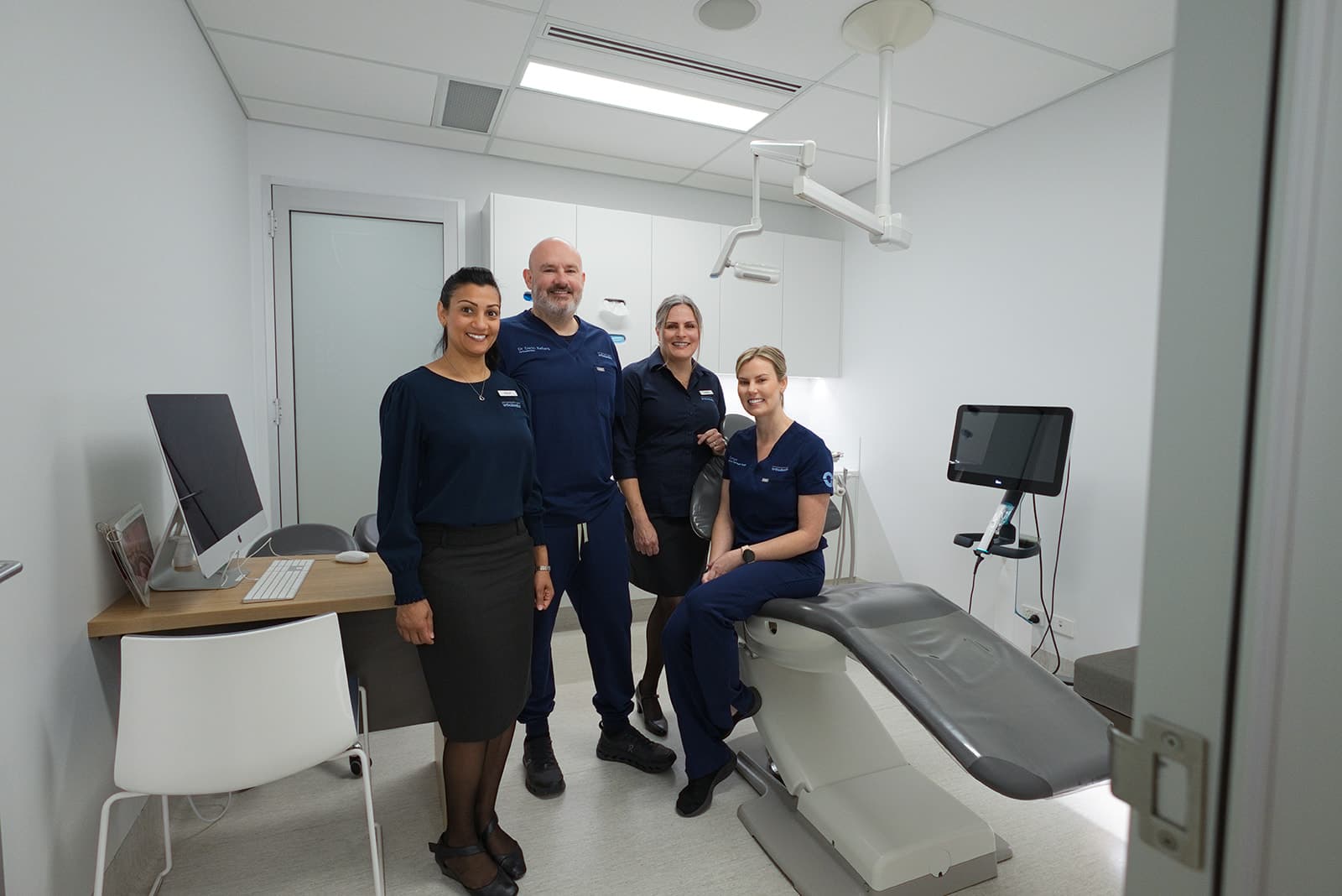 Orthodontist and team posing together in a bright treatment room