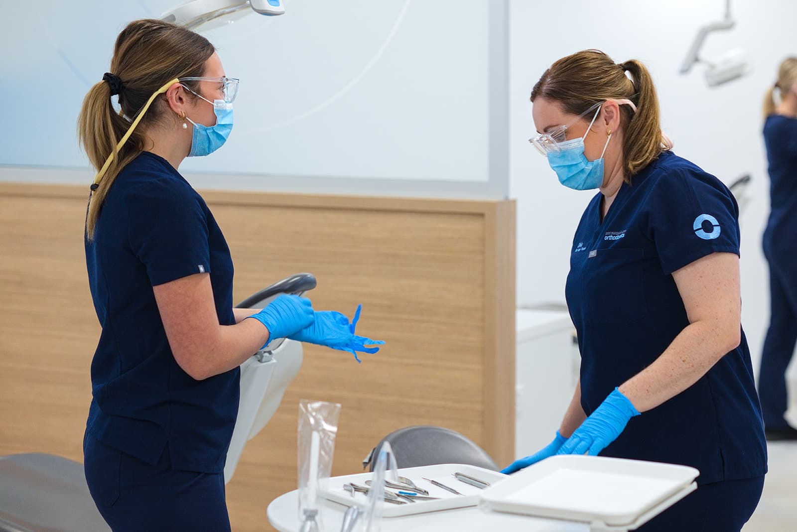 Two masked clinicians preparing an instrument tray
