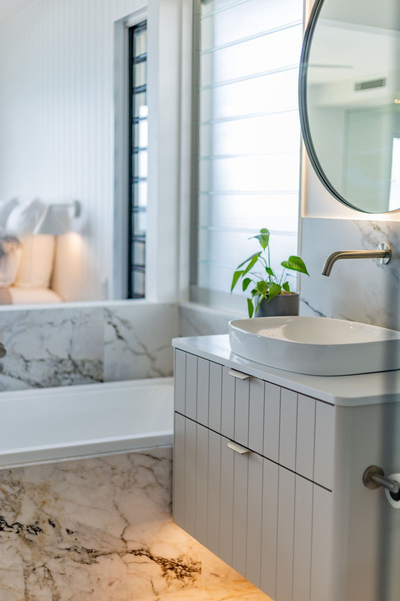 Bathroom with marble walls, vessel basin and plant