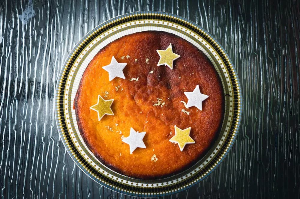 Orange cake topped with gold stars on a decorative plate