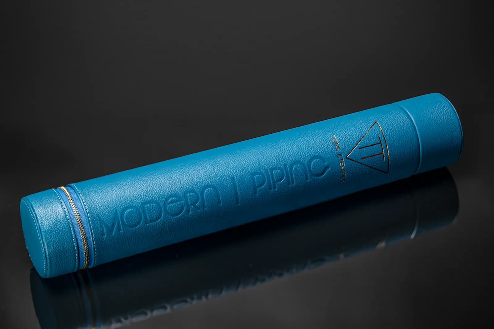 Embossed blue leather tube case on a dark surface