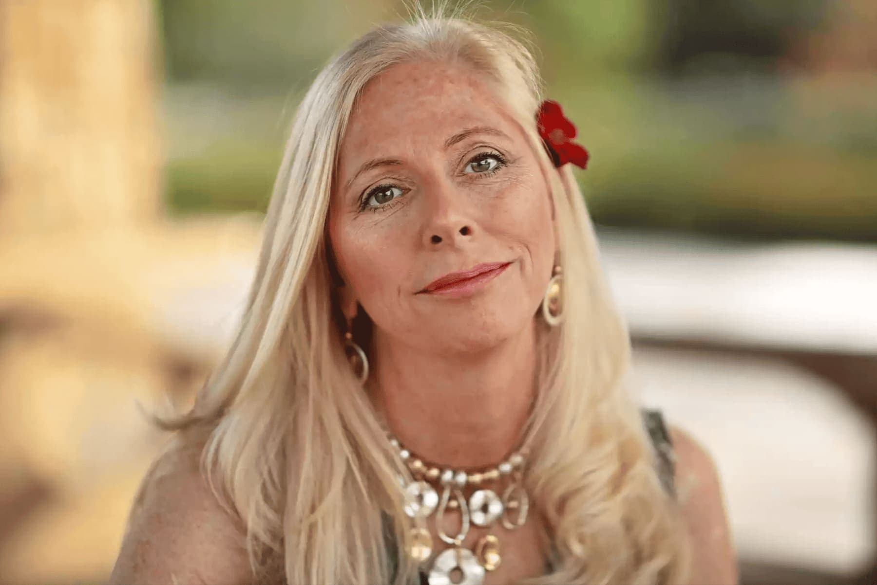 Portrait of a woman with long blonde hair and a red flower