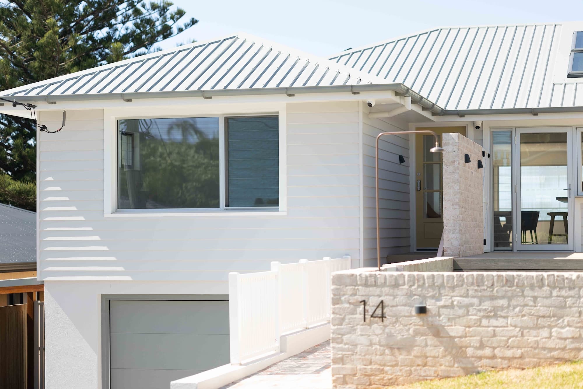 White weatherboard coastal home with a limewashed brick front wall