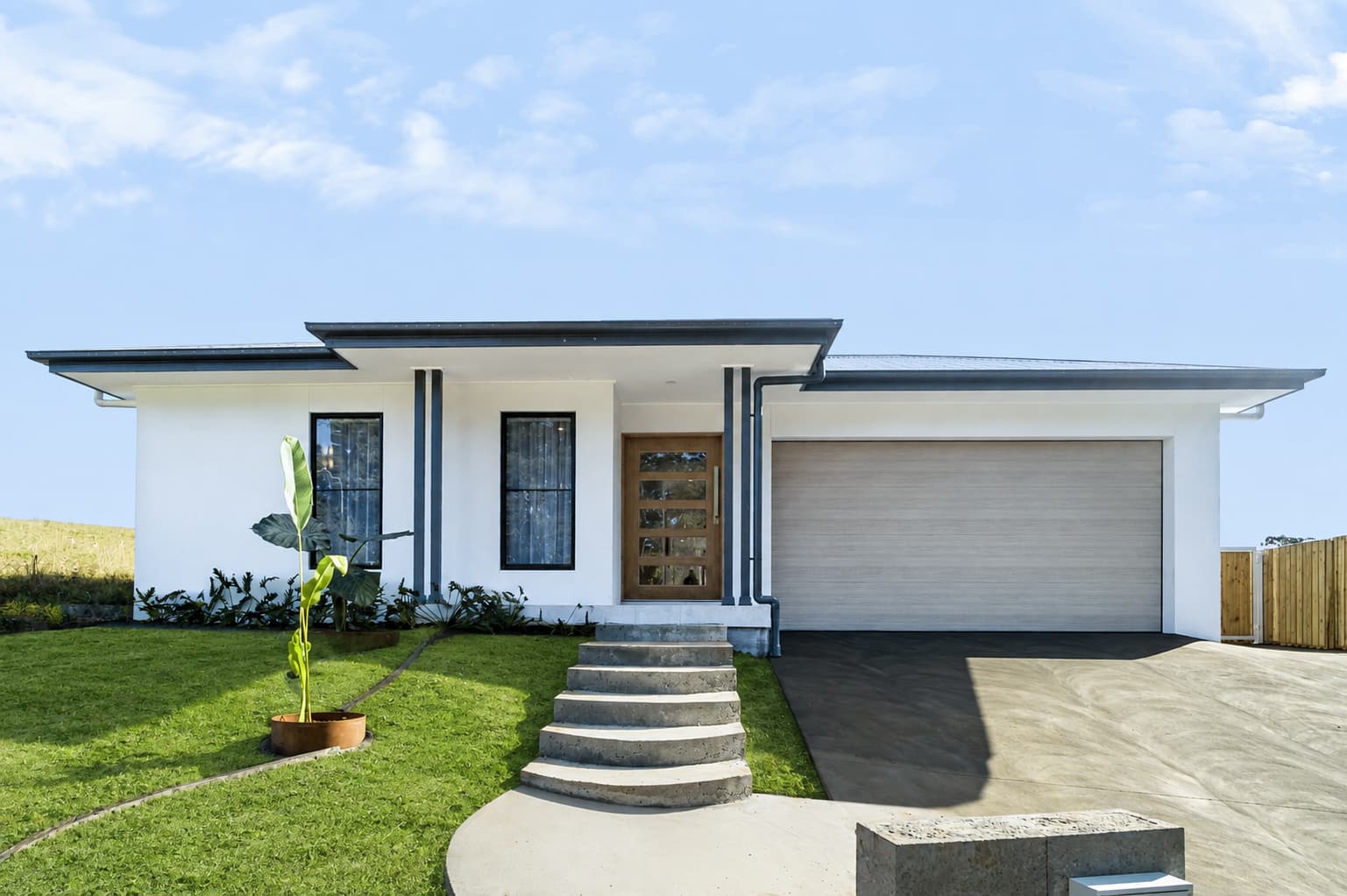 Front facade of a new white build with timber door and curved steps