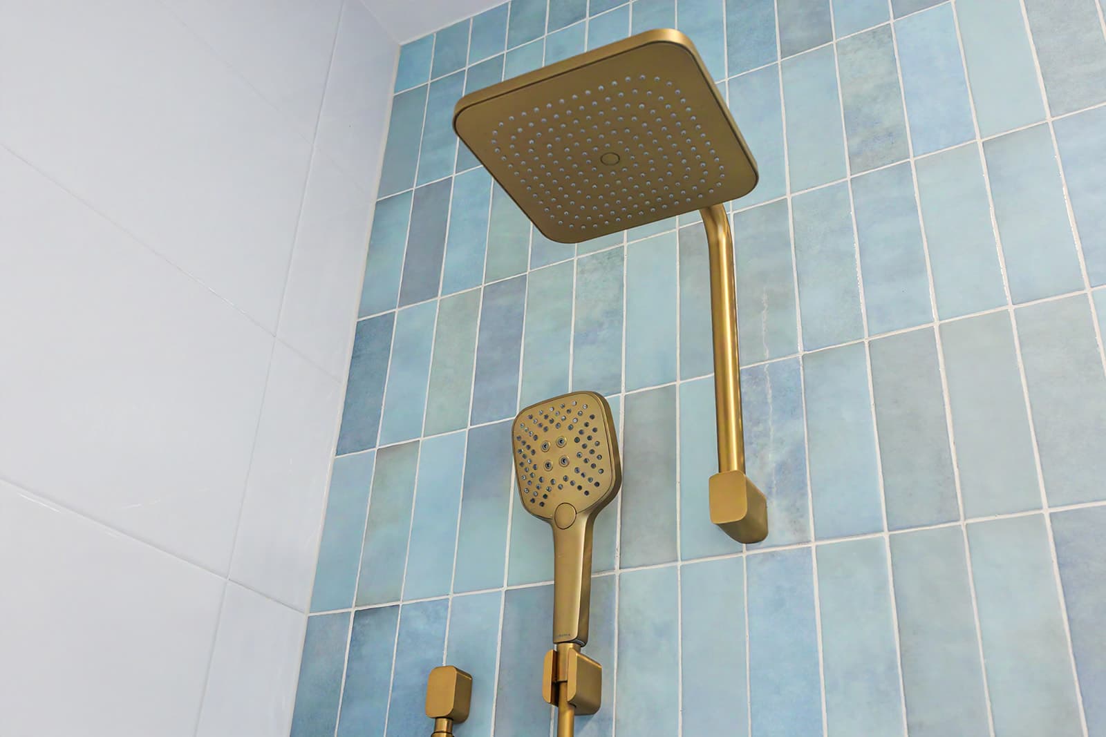 Brushed brass rain shower against blue gloss tiles