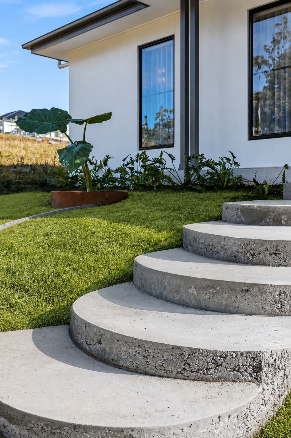 Curved concrete entry steps and tropical garden bed