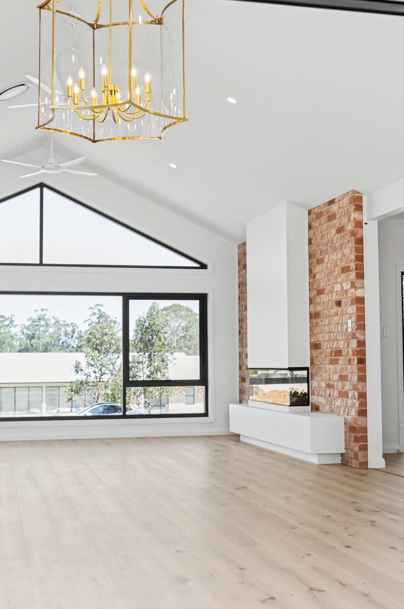 Raked-ceiling living room with a brass lantern chandelier and brick fireplace