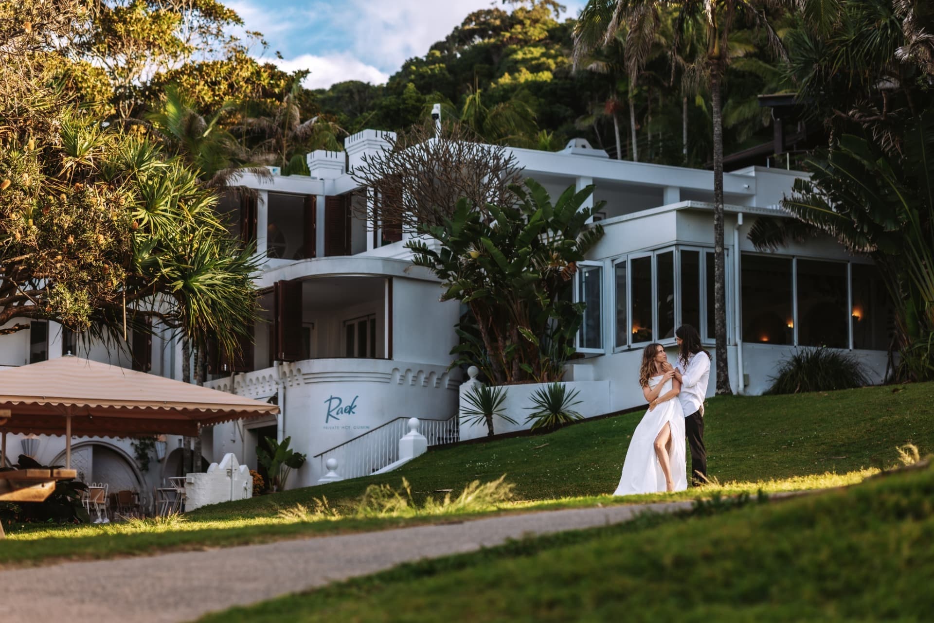 Newlyweds on the lawn in front of a white coastal venue