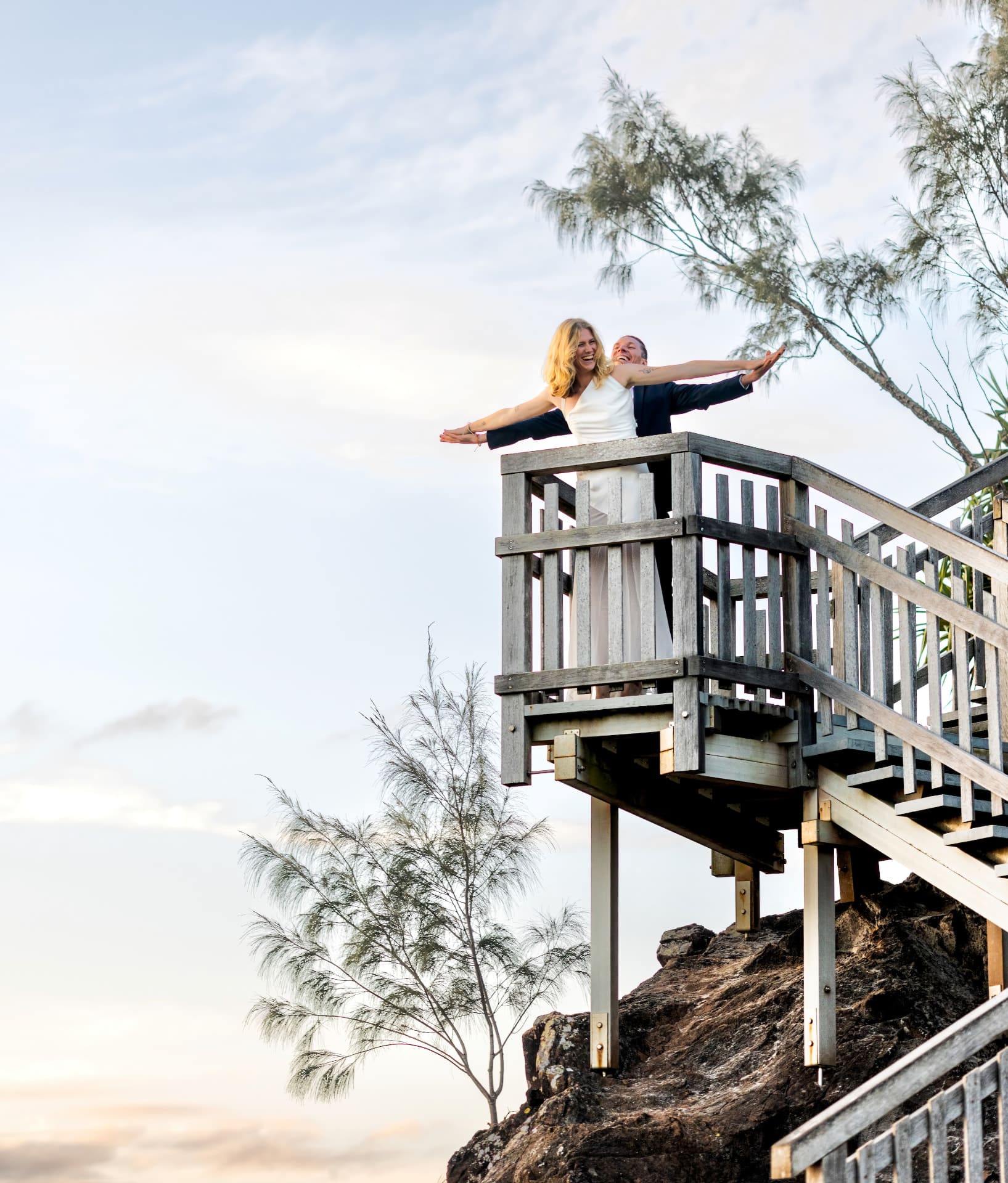 Groom lifting the bride on a coastal lookout with the ocean behind